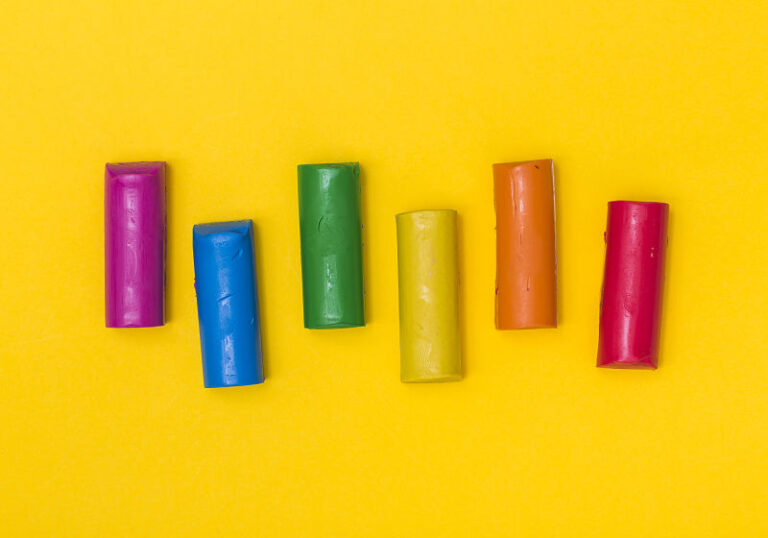 Imagem com fundo amarelo e bastões de massinha de diversas cores