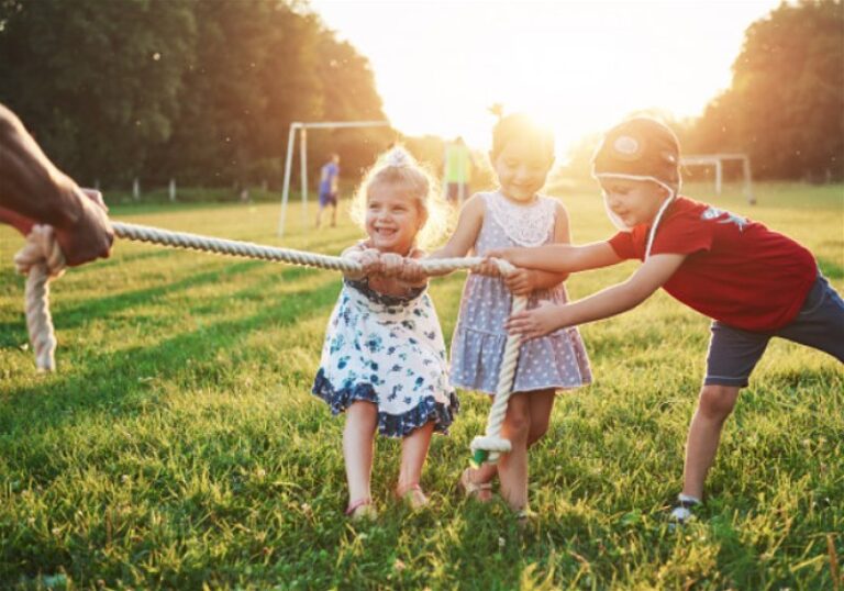 Crianças brincando de cabo de guerra em gramado