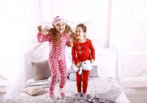 Meninas vestidas de pijama, pulando em cama