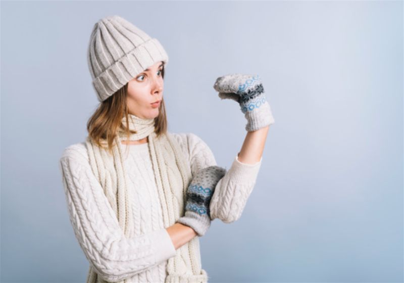 Mulher com roupa de frio e luva, imitando fantoche com as mãos