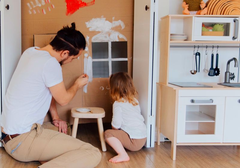 Pai e filha pintando em uma sala de brinquedos.