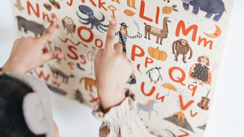 criança vendo alfabeto em papel de parede lúdico