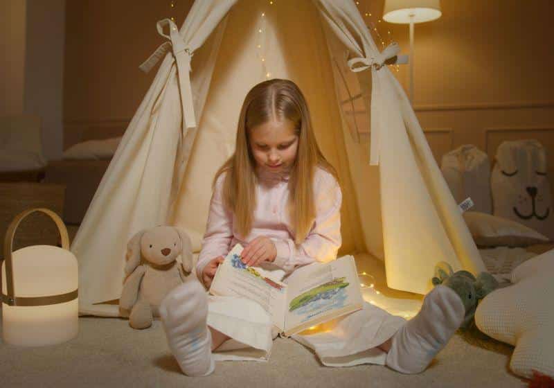 Criança lendo em seu quarto dentro de cabana.